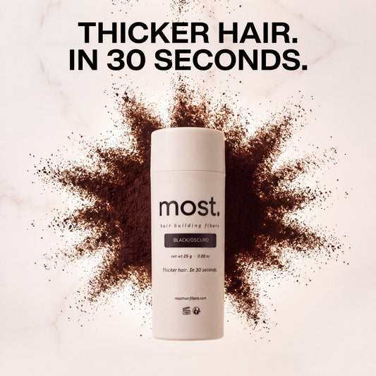A bottle of most. hair fibers on marble inside a burst of dark brown fiber powder, headline Thicker hair. In 30 seconds.